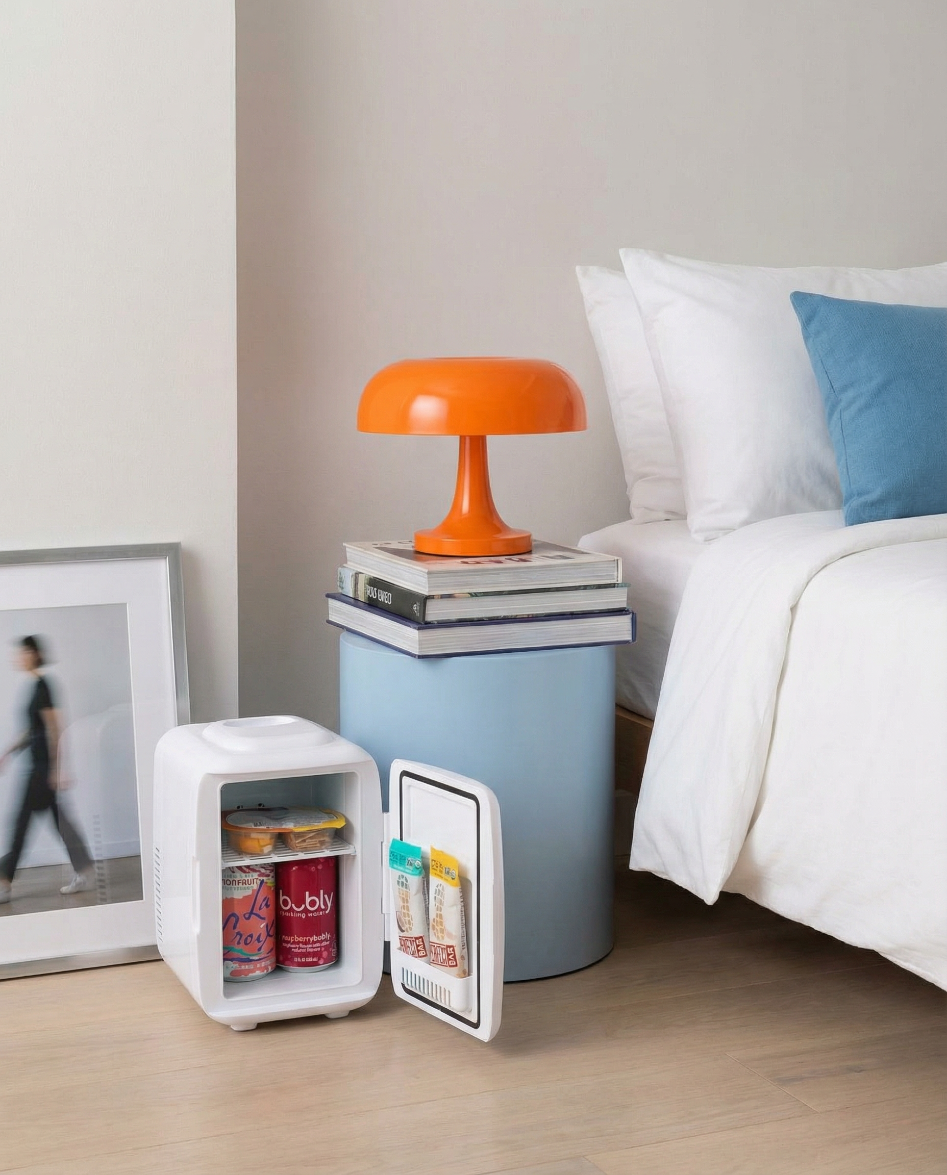 Generated_with_Kive.ai_-_Minimalist_bedroom_corner_vignette__powder_blue_cylindrical_nightstand_with_stacked_art_books__tangerine_modernist_desk_lamp__White_mini_fridge_with_snacks__c.png
